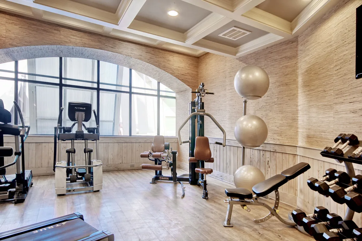 A modern fitness center filled with exercise machines, dumbbells, and large windows streaming sunlight. The space feels energetic and motivating, ideal for guests wanting to stay active during their stay.
