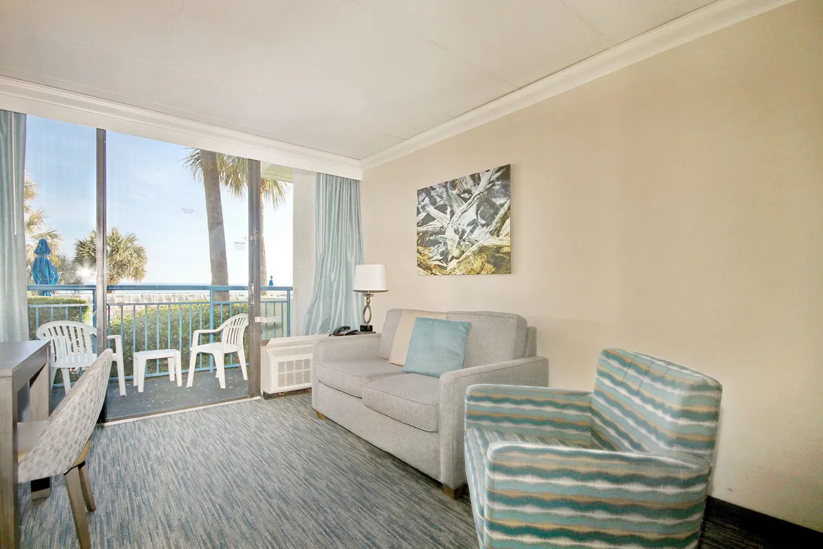 A comfortable living area with large windows providing an ocean view, plush seating, and abstract wall art. The space feels casual and welcoming, hinting at moments of laughter, conversation, and relaxation after a day of exploration.